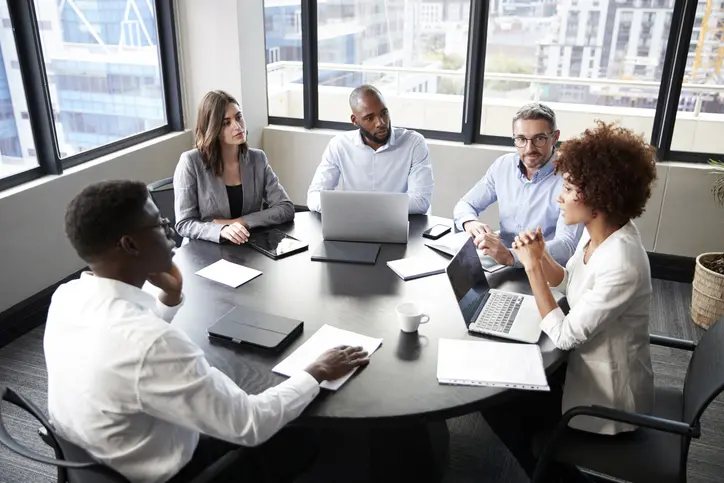 A diverse team engaged in a collaborative meeting around a conference table.