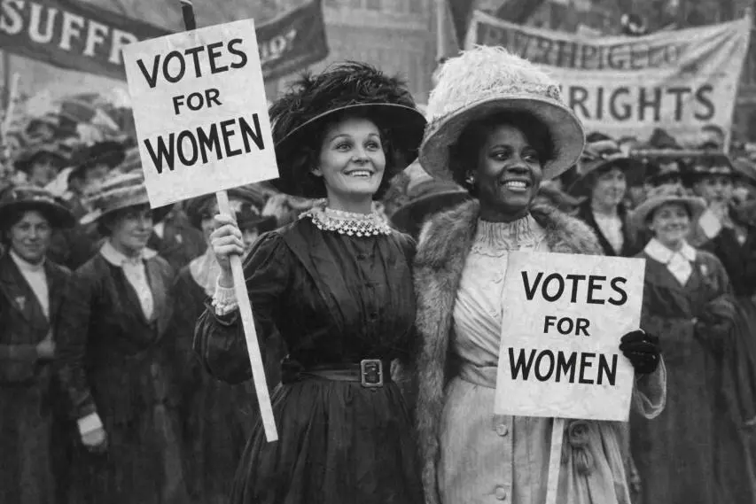 Two women hold 'Votes for Women' signs during a suffrage rally.
