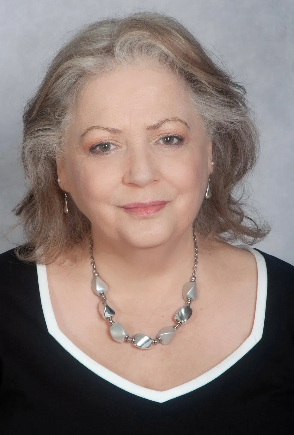 Portrait of a smiling older woman with gray hair and a pearl necklace.